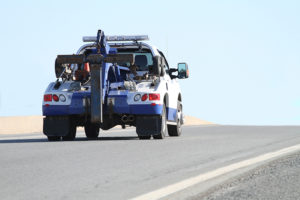 Rear quarter view of a nondescript tow truck traveling on a highway.
